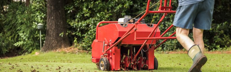 Man using gas powered aerating machine to aerate lawn